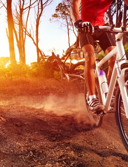 Radfahrer auf einem Feldweg bei Sonnenuntergang.