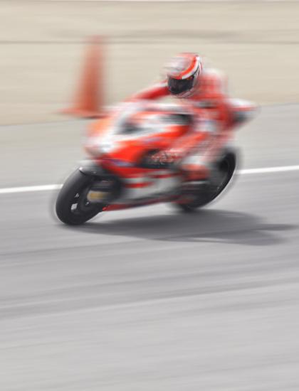 Motorcycle racing fast on track with blurred background.