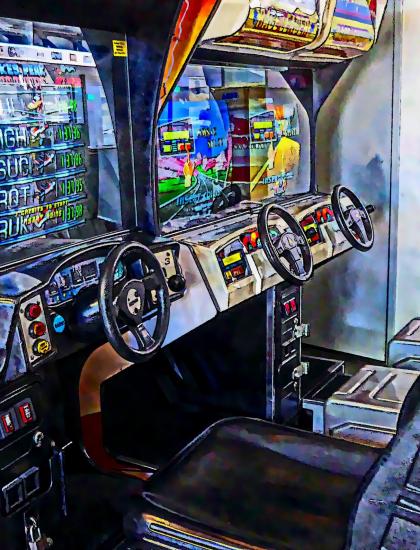 Arcade driving cabin with two steering wheels and screens.