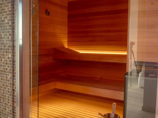 Modern sauna with wood and bucket, warm lighting.