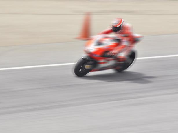 Motorcycle racing fast on track with blurred background.