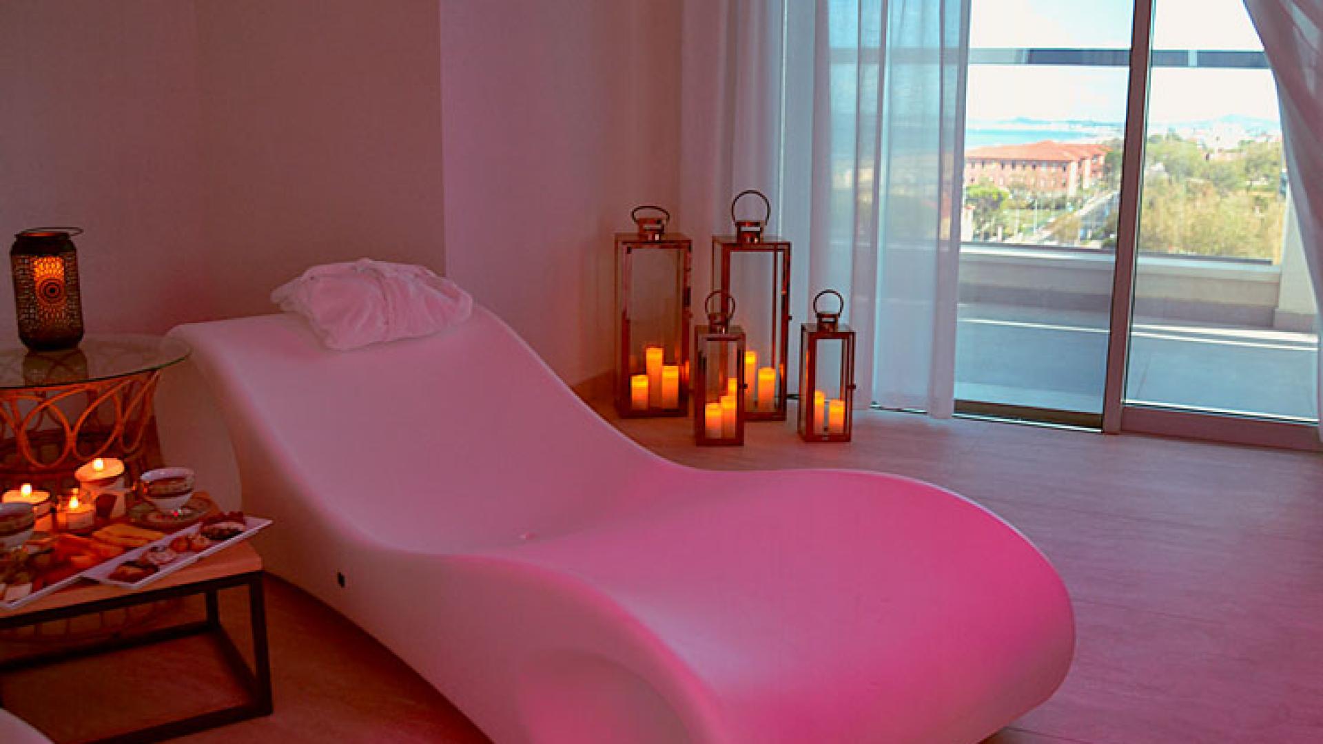 Salle de détente avec chaise longue, bougies et vue panoramique.